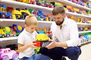 A young boy selects a toy with guidance from an adult