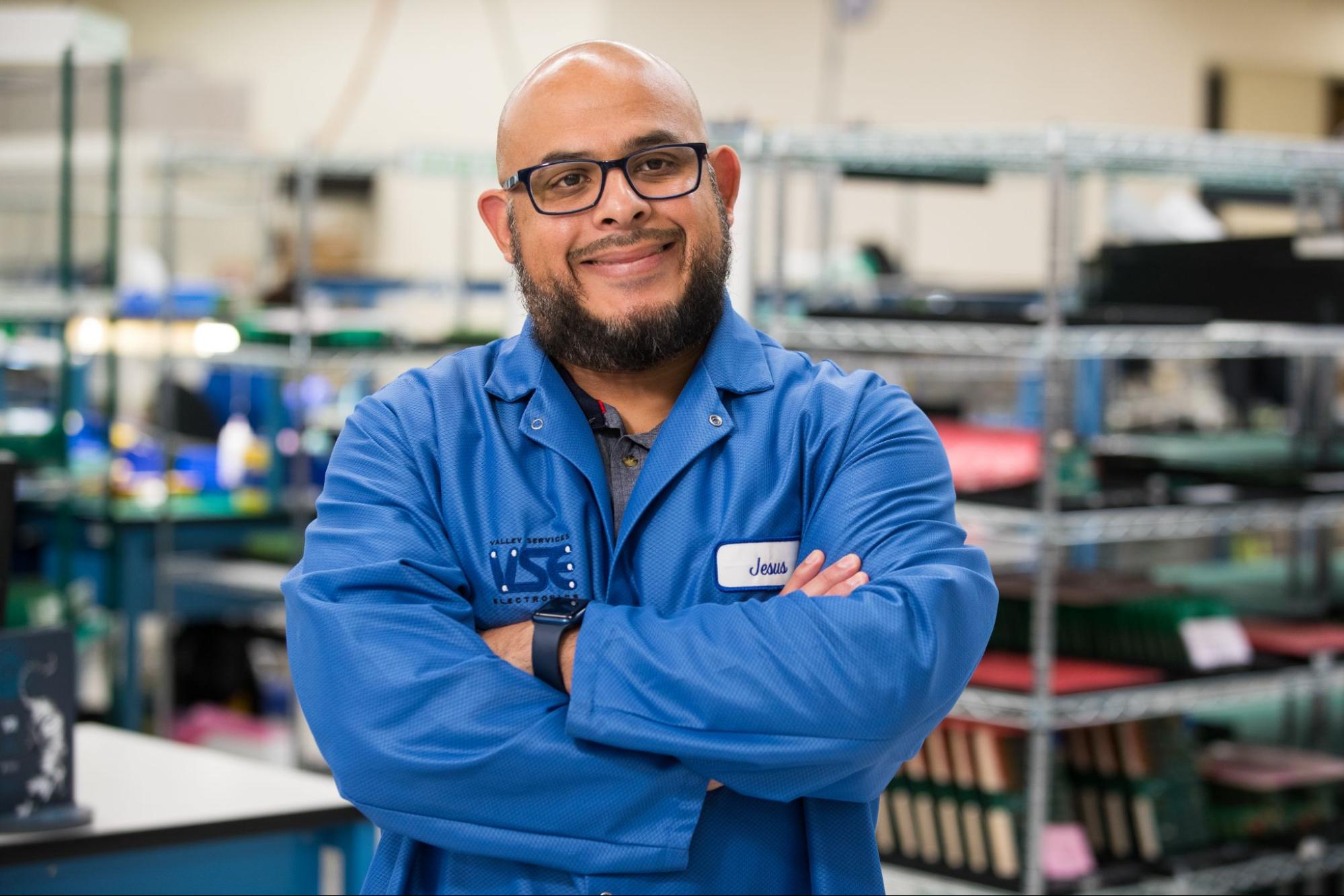 A man wearing a blue lab coat and glasses smiles with his arms crossed. A man wearing a blue lab coat and glasses smiles with his arms crossed.